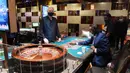 Dealer Gary Reed terlihat saat Tilak Fernando dan Dred Phillips bermain rolet di hotel dan kasino Bellagio, Las Vegas, Nevada, AS, Kamis (4/6/2020). Kasino di Nevada diizinkan kembali beroperasi setelah penutupan sementara untuk mencegah penyebaran COVID-19. (Ethan Miller/Getty Images/AFP)