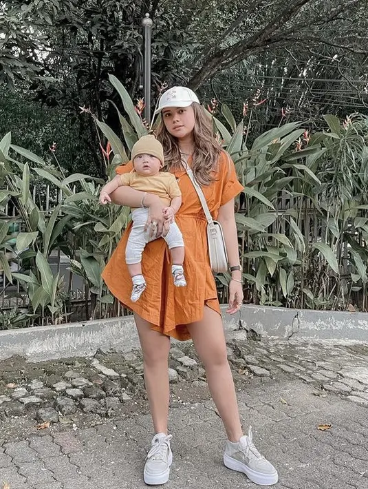 Dress orange pun dipilih oleh Audi ketika hangout bareng si kecil. Ia tampak mengenakan topi cap dengan warna senada dengan sling bag dan sneakersnya. @audimarissa