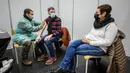 Tentara Swiss memberikan suntikan vaksin booster COVID-19 kepada seorang pria di sebelah istrinya di Delemont, Swiss, 14 Desember 2021. Swiss yang dilanda gelombang infeksi baru COVID-19 telah memanggil tentara untuk mempercepat vaksinasi.
(Fabrice COFFRINI/AFP)
