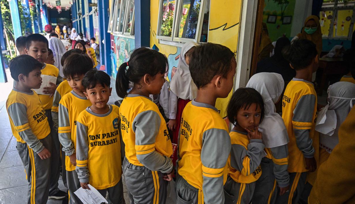 Para siswa mengantre untuk menerima vaksin difteri di sebuah sekolah dasar di Surabaya pada Selasa 4 November 2025. Program yang menyasar seluruh siswa SD, MI, SMP, dan MTs di Kota Surabaya dan dilaksanakan secara gratis di sekolah masing-masing oleh tim dari Puskesmas setempat. (Juni KRISWANTO/AFP)