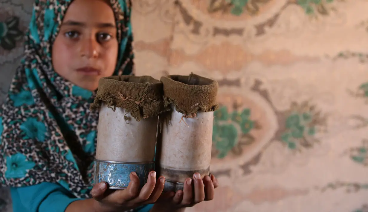 Maya Mohammad Ali Merhi (8) menunjukan kaki prostetik dari kaleng di sebuah kamp orang terlantar di Provinsi Idlib, Suriah, Rabu (20/6). Keluarga Maya meninggalkan rumah mereka di Provinsi Aleppo untuk melarikan diri dari pertempuran. (Aaref Watad/AFP)