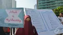 Seorang perempuan berdiri di depan Alquran raksasa yang dibawa mengelilingi Bundaran HI, Jakarta, Minggu (21/12/2014). (Liputan6.com/Herman Zakharia)