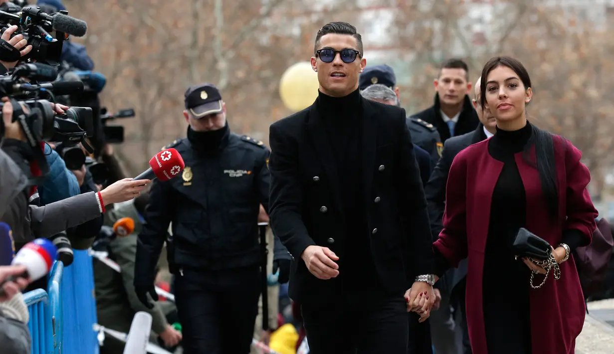 Pemain Juventus Cristiano Ronaldo menggandeng kekasihnya Georgina Rodriguez saat tiba di pengadilan di Kota Madrid, Selasa (22/1). Selain Ronaldo, Xabi Alonso juga dijadwalkan hadir dalam kasus serupa. (AP Photo/Manu Fernandez)