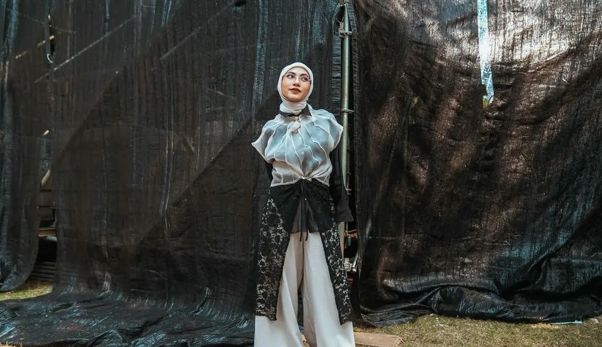 Tampil unik, Feby memadukan kemeja hitam dengan outer tuller semi transparan. Celana kulot dengan aksen brukat bikin tampilannya kian estetik [@fbyputrinc]