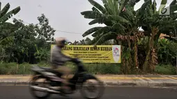 Motor melintas di dekat spanduk larangan di kawasan Pulomas, Jakarta, Rabu (4/7). Larangan berjualan hewan kurban radius 1 kilometer dari Equestrian Park bagian dari sterilisasi. (Merdeka.com/Iqbal S. Nugroho)