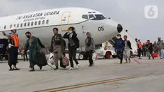 Tiga Warga Negara Indonesia (WNI) yang dipulangkan dari Sudan berjalan setibanya di Pangkalan Udara Halim Perdanakusuma, Jakarta, Senin (1/5/2023). Sebanyak 75 WNI tiba di tanah air dari Sudan dengan menggunakan pesawat TNI AU. (Liputan6.com/Helmi Fithriansyah)