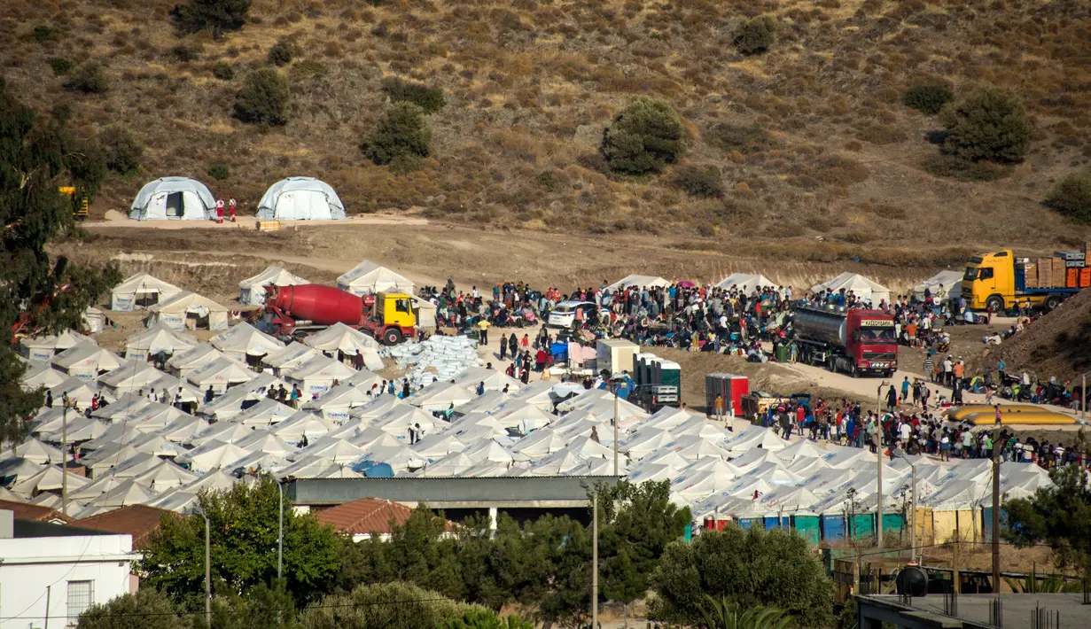 Migran berkumpul di kamp tenda sementara yang baru di Kara Tepe, Lesbos, Yunani, Kamis (17/9/2020). Lebih dari 5.000 pencari suaka yang kehilangan tempat tinggal setelah kebakaran kamp migran terbesar di Yunani, Kamp Moria, kini telah ditempatkan di fasilitas baru. (AP Photo/Panagiotis Balaskas)