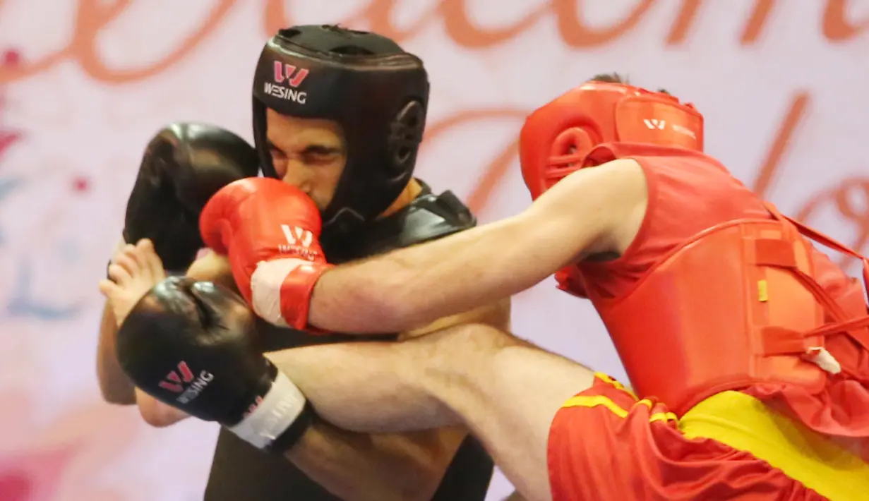 Atlet Wushu Asal Mesir, Aymen Mohamed (kiri) mendapat pukulan  Atlet Rusia, Ali  pada Cabang Sanda Kejuaraan Dunia Wushu 2015 di Istora, Senayan, Jakarta,Rabu (18/11/2015). (Bola.com/Nicklas Hanoatubun)