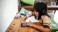 Seorang siswi memperhatikan ponsel saat belajar secara daring di Jakarta, Rabu (4/11/2020). Usulan perubahan sistem Pembelajaran Jarak Jauh dari Federasi Serikat Guru Indonesia kepada Kemendikbud terkait adanya tiga siswa yang mengakhiri hidupnya diduga lantaran depresi. (Liputan6.com/Faizal Fanani)