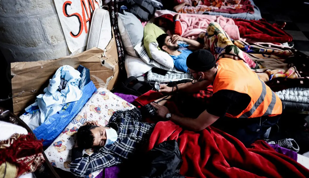 Seorang relawan paramedis merawat seorang migran yang mogok makan saat ia menduduki Gereja Saint-Jean-Baptiste-au-Beguinage di Brussel, Belgia, Rabu (2/6/2021). Ratusan migran, 220 di antaranya mogok makan selama 11 hari, menempati gereja ini sejak 31 Januari 2021. (Kenzo TRIBOUILLARD/AFP)