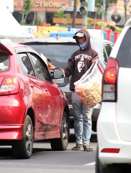 Pedagang asongan menjajakan dagangannya di Jalan Margonda Raya, Depok, Kamis (16/4/2020).  Menko Bidang Perekonomian Airlangga Hartarto mengungkap proyeksi pemerintah terhadap angka kemiskinan naik dari 9,15 persen menjadi 9,59 persen akibat pandemi COVID-19. (Liputan6.com/Helmi Fithriansyah)