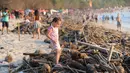 Seorang gadis melintas di atas sampah yang terdampar akibat cuaca buruk di Pantai Kuta, Bali, Jumat (15/2). Sampah bervolume besar kembali menepi di Pantai Kuta, kali ini pesisir pantai berpasir putih itu dipenuhi sampah buah kelapa. (SONNY TUMBELAKA/AFP)