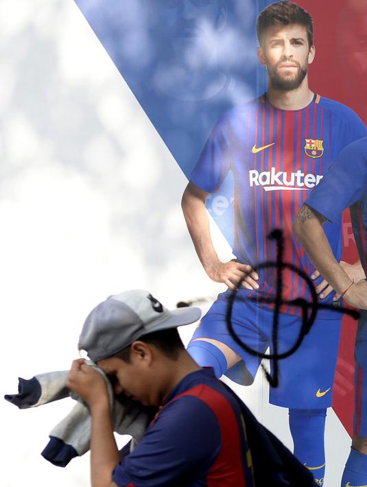 Poster Gerard Pique yang dirusak di sebuah toko di luar stadion Camp Nou, Barcelona (3/10). Bek Barcelona ini terang-terangan mendukung Catalonia untuk memerdekakan diri. (AFP Photo/Josep Lago)