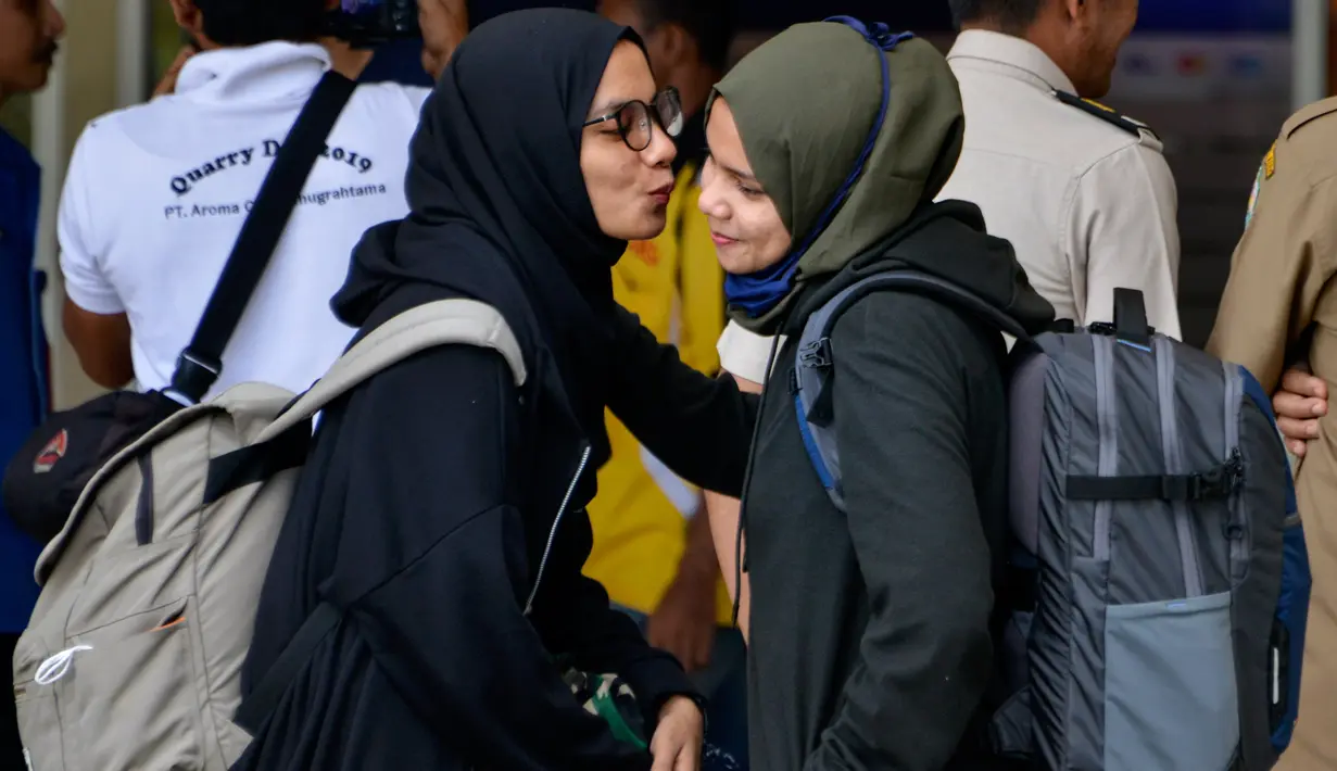 Seorang mahasiswa (kanan) yang dipulangkan dari karantina virus corona atau COVID-19 di Natuna memeluk keluarganya saat tiba di Bandara Internasional Sultan Iskandar Muda, Blang Bintang, Aceh, Senin (17/2/2020). Kepulangan mahasiswa Aceh ini disambut suka cita keluarga. (CHAIDEER MAHYUDDIN/AFP)