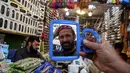Rata-rata, mereka mencari bahan makanan, buah-buahan untuk berbuka puasa hingga pakaian. Tampak dalam foto, seorang pria mencoba topi tradisional yang akan digunakan saat berdoa selama bulan puasa Ramadan, di sebuah toko di Peshawar, Pakistan, Senin, 16 Februari 2026. (AP Photo/Muhammad Sajjad)
