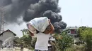 Warga menyelamatkan harta bendanya saat kebakaran melanda gardu induk PLN di Kembangan, Jakarta Barat, Rabu (2/9/2015). Akibat kebakaran ini, PLN terpaksa memadamkan jaringan listrik di sejumlah titik di Jakarta dan Tangerang.(Liputan6.com/Gempur M Surya)