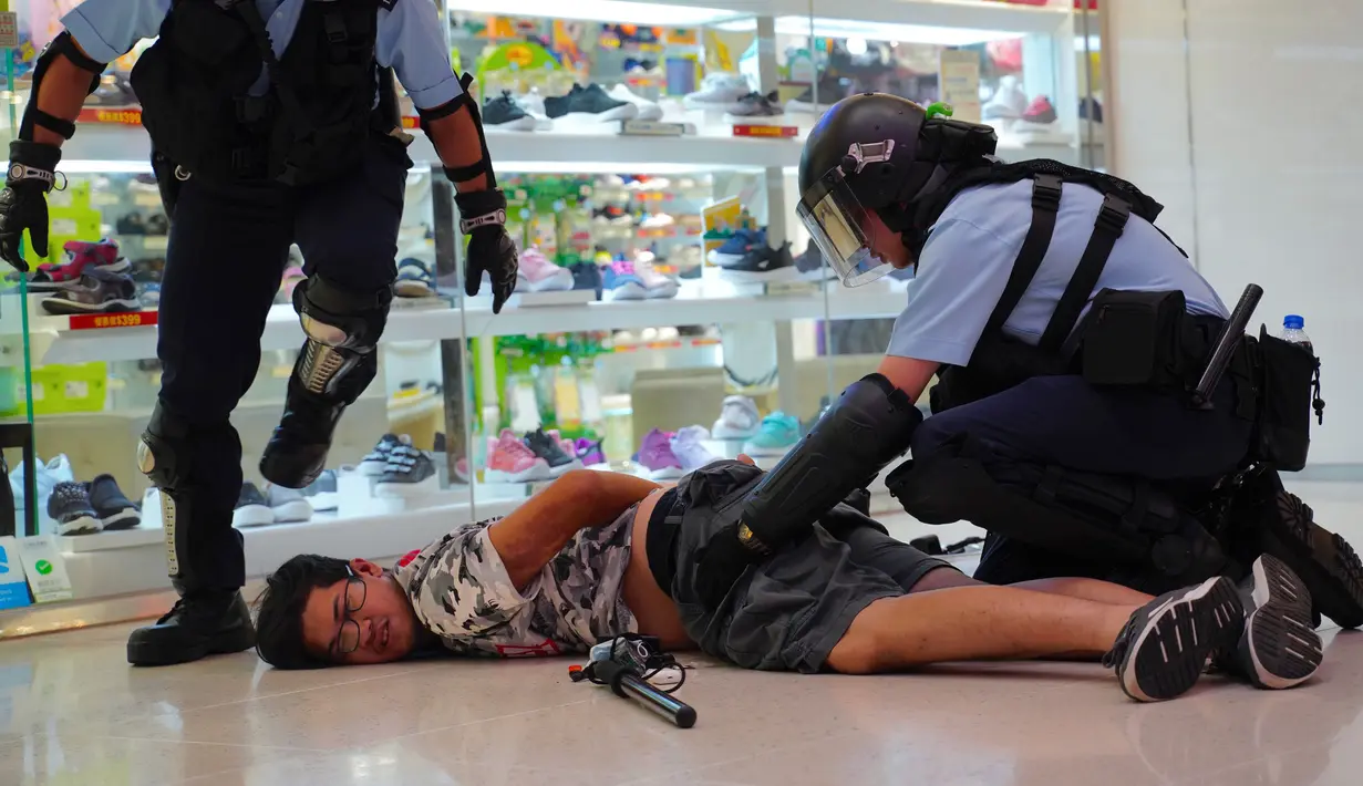 Polisi menahan seorang pria muda setelah perkelahian antara demonstran pro China dengan demonstran antipemerintah di Amoy Plaza, Distrik Kowloon Bay, Hong Kong, Sabtu (14/9/2019). Personel Kepolisian Hong Kong yang bersenjatakan tongkat dikerahkan untuk menangani bentrokan. (AP Photo/Vincent Yu)