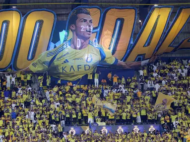 Publik Al-Nassr merayakan rekor gol ke-900 milik Cristiano Ronaldo saat laga lanjutan Liga Arab melawan Al-Ahli yang berlangsung di Al-Awwal Stadium, Riyadh, Jumat (13/09/2024) waktu setempat. Para suporter terlihat membentangkan banner raksasa bertuliskan 900 goals dengan gambar sang pemain. (AFP/Fayez Nureldine)