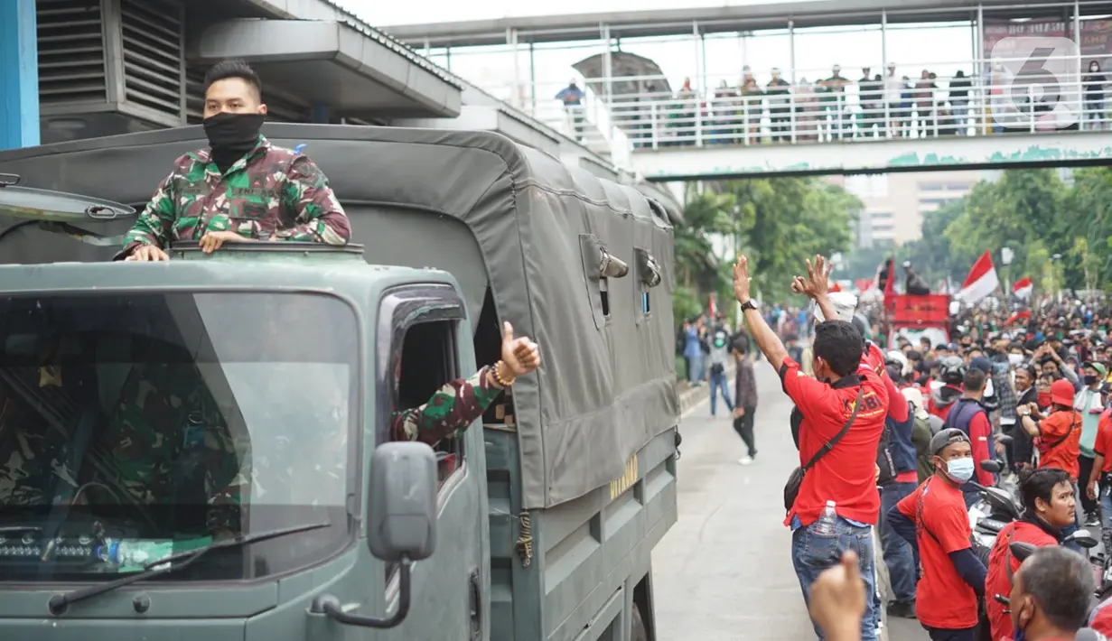 Pengunjuk rasa menyapa kendaraan TNI yang melintas di Jalan Salemba Raya, Jakarta, Kamis (8/10/2020). Banyaknya jumlah pengunjuk rasa yang berjalan menuju Istana Negara menyebabkan Jalan Salemba Raya dari arah Matraman tertutup dan tidak bisa dilalui kendaraan. (Liputan6.com/Immanuel Antonius)