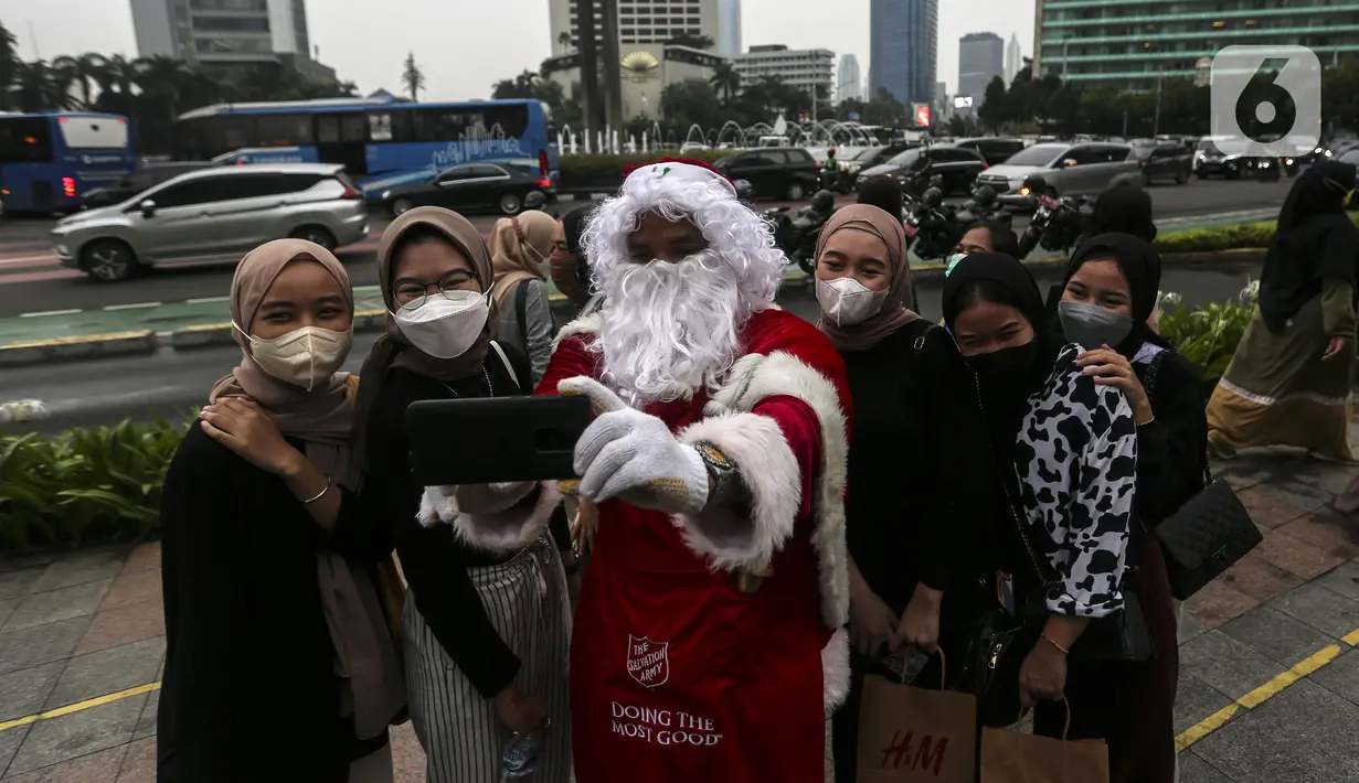 Seorang berpakaian sinterklas berfoto dengan warga saat acara Christmas in Jakarta di Bundaran Hotel Indonesia, Jakarta, Selasa (21/12/2021). Pemerintah Provinsi DKI Jakarta menggelar Christmas in Jakarta dalam rangka menyambut Natal 2021. (Liputan6.com/Johan Tallo)