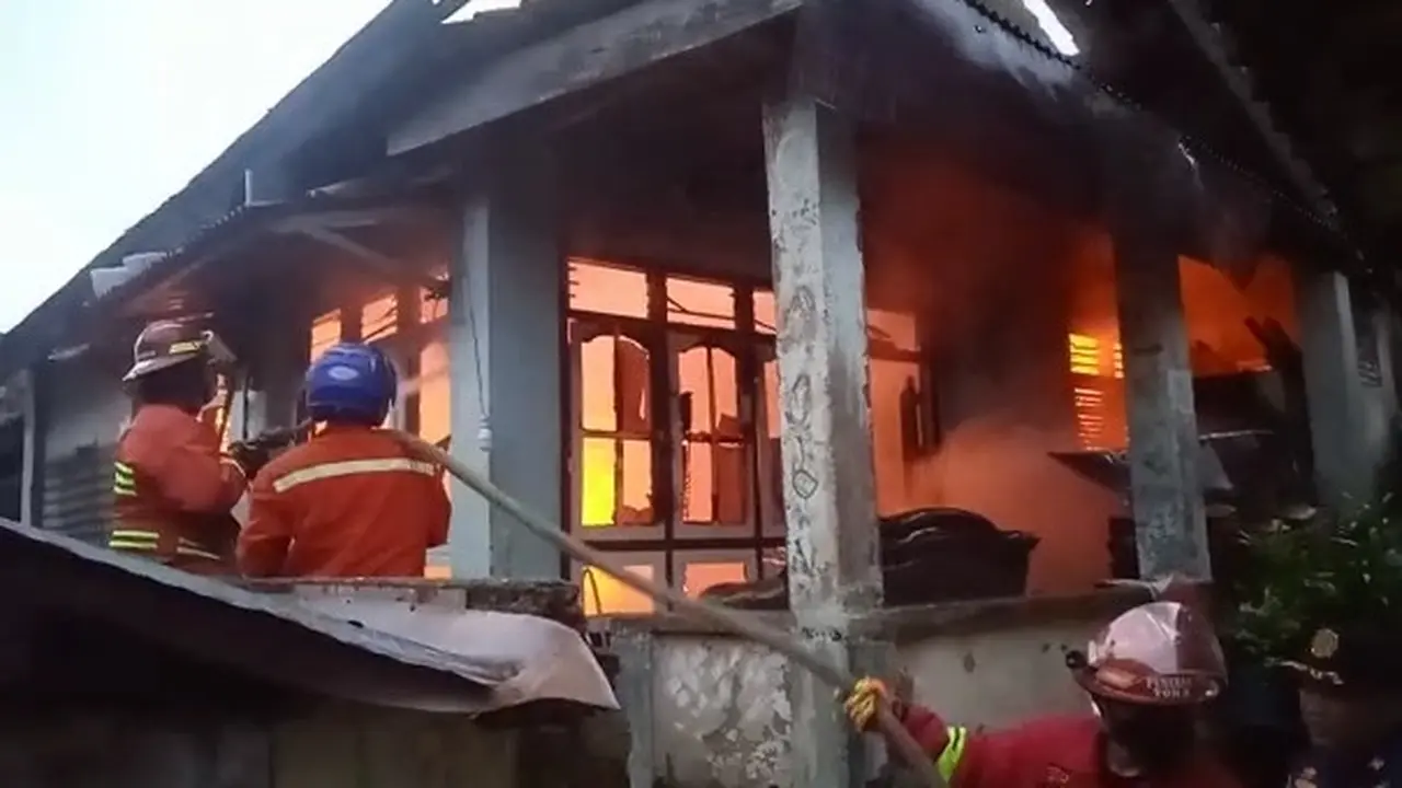 Petugas Damkar memadamkan kebakaran rumah.
