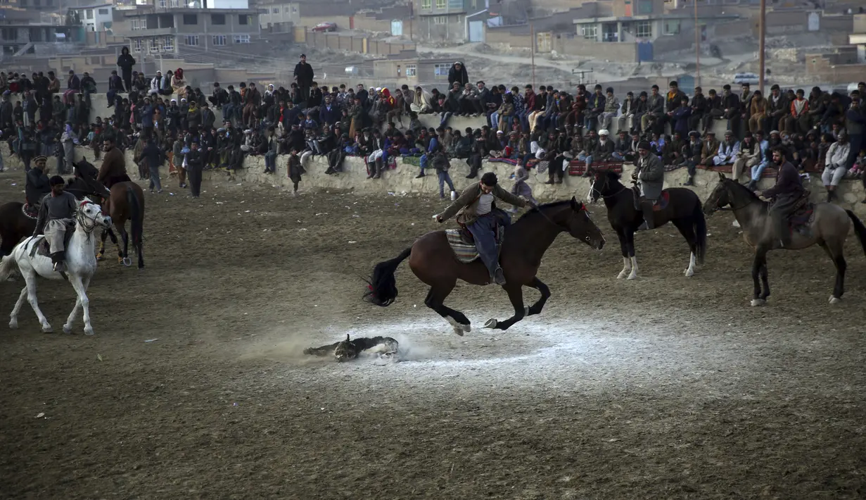 Penunggang kuda berebut kambing pada pertandingan persahabatan buzkashi di pinggiran Kabul, Afghanistan, Jumat (27/12/2019). Buzkashi adalah olahraga tradisional Afghanistan di mana para pemainnya berlomba untuk menempatkan bangkai kambing ke dalam lingkaran. (AP Photo/Rahmat Gul)