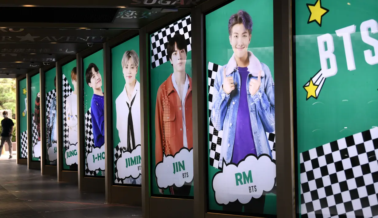 Warga melewati poster komersial anggota boyband K-pop, BTS, di luar toko bebas pajak di Seoul, Selasa (1/9/2020). Lagu "Dynamite" puncaki tangga lagu Billboard dan membuat BTS menjadi penyanyi Kpop sekaligus grup Asia pertama yang meraih posisi nomor satu di Billboard Hot 100. (Jung Yeon-je/AFP)