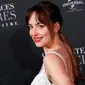 Dakota Johnson tersenyum saat menghadiri penayangan perdana film terbarunya, Fifty Shades Freed di Salle Pleyel di Paris, Prancis (6/2). Aktris 28 tahun ini tampil cantik dan seksi dengan gaun putih yang dikenakannnya. (AP Photo/Francois Mori)