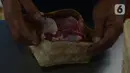 Petugas memasukan daging ke besek di Rumah Pemotongan Hewan (RPH) Dharma Jaya, Jakarta, Rabu (21/7/2021). Dimana RPH Dharma Jaya menerima pemotongan sebanyak 600 ekor sapi dengan penerapan protokol kesehatan saat penyembelihan dengan tes swab sebelum bekerja.  (merdeka.com/Imam Buhori)