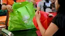 Karyawan mengemas barang belanjaan konsumen dengan tas belanja nonplastik di sebuah supermarket di Denpasar, 16 Juli 2019. Bali menerapkan pelarangan penggunaan plastik sekali pakai yang tertuang dalam Peraturan Gubernur (Pergub) Nomor 97 Tahun 2018. (SONNY TUMBELAKA/AFP)
