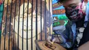 Anak Arfan (55) menyelesaikan karya seni lukis bakar di galeri Rumah Oenik, Kampung Ragamukti, Bogor, Senin (28/9/2020). Menggunakan limbah kayu dan kulit yang tidak terpakai Arfan mengubah dengan menggunakan solder listrik  menjadi karya seni yang bernilai tinggi. (merdeka.com/Arie Basuki)