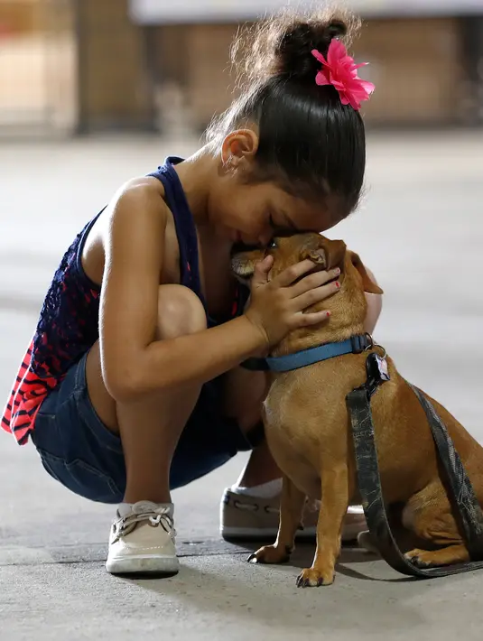 Reniah Knight memeluk anjingnya di NRG Arena di Houston (13/9). Relawan mengamankan 400 anjing dan 100 kucing untuk membantu menyatukan pemilik dengan hewan peliharaannya yang hilang akibat Badai Harvey. (Karen Warren/Houston Chronicle via AP)