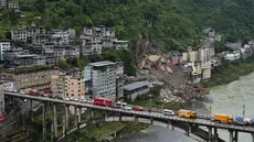 Kendaraan penyelamat bersiaga di jembatan saat tim penyelamat melakukan operasi pencarian dan penyelamatan di lokasi tanah longsor di Kabupaten Pengshui, Chongqing, Tiongkok barat daya, Sabtu, 18 Juli 2026. (AP Photo/Andy Wong)