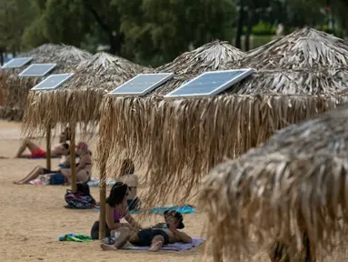 Panel surya terpasang pada sejumlah payung di pantai dekat Balai Kota Vari-Voula-Vouliagmeni, Yunani, Selasa (21/7/2020). Puluhan payung di sepanjang pantai tersebut dilengkapi sistem panel surya dan port USB untuk menyediakan pengisian daya gratis dan ramah lingkungan. (Xinhua/Lefteris Partsalis)