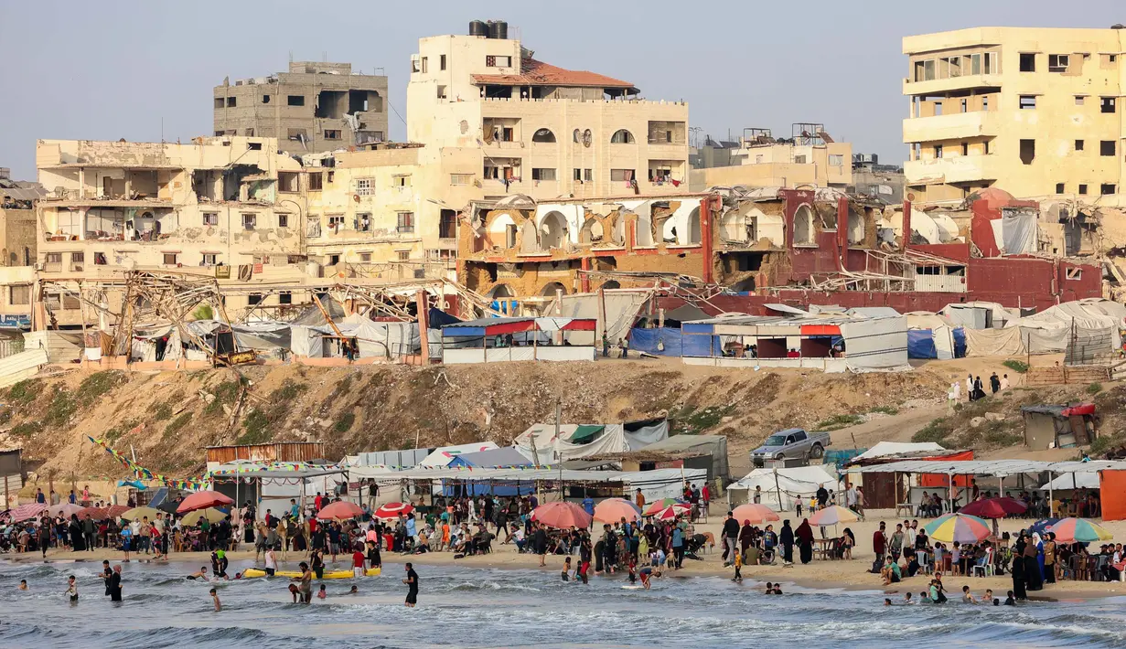 Warga Palestina berkumpul di pantai, kota Gaza untuk menghindari panas dan tenda pengungsian di tengah perang yang sedang berlangsung antara Israel dan milisi Hamas pada 8 Juni 2025. (Omar AL-QATTAA/AFP)