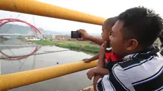 Warga mengabadikan kendaraan pemudik yang melintasi Jembatan Kali Kuto di ruas tol fungsional Batang-Semarang, Gringsing, Jateng, Rabu (13/6). Berfungsinya Jembatan ini akan memperlancar arus mudik dan arus balik Lebaran 2018. (Liputan6.com/Arya Manggala)