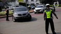 Petugas polisi mengarahkan kendaraan berplat nomor genap di pos penyekatan ganjil-genap di Bundaran Senayan, Minggu (5/9/2021). Pembatasan kendaraan dengan sistem pelat nomor kendaraan ini tetap berlaku di akhir pekan, Sabtu dan Minggu. (Liputan6.com/Angga Yuniar)