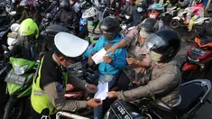 Petugas polisi memeriksa kelengkapan Surat Tanda Registrasi Pekerja  (STRP) bagi pengendara bermotor pada pos  perpanjangan Pemberlakuan Pembatasan Kegiatan Masyarakat (PPKM) Jalan Raya Ir.H.Djuanda, depan Sandratex, Tangerang Selatan, Kamis (15/07/2021). (merdeka.com/Arie Basuki)