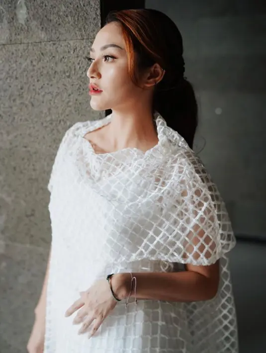 Pelantun lagu "Lagi Syantik" saat pakai outfit gaun putih dengan hiasan atasan jaring-jaring itu membutanya terkesan flawless namun tetap simpel. (Liputan6.com/IG/@sitibadriahh)