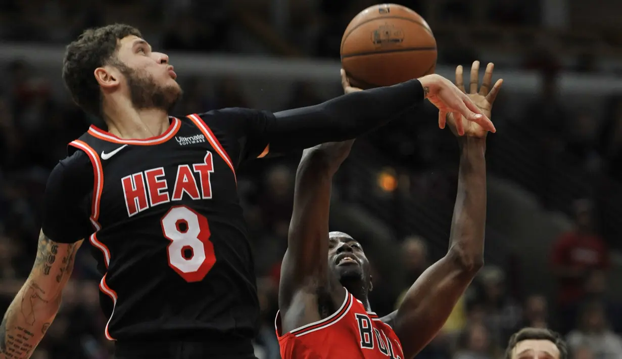 Pemain Miami Heat, Tyler Johnson menghalau tembakan pemain Chicago Bulls, Jerian Grant (kanan) pada laga NBA basketball game di United Center, Chicago, (26/11/2017). Miami Heat menang 100-93.  (AP/Paul Beaty)