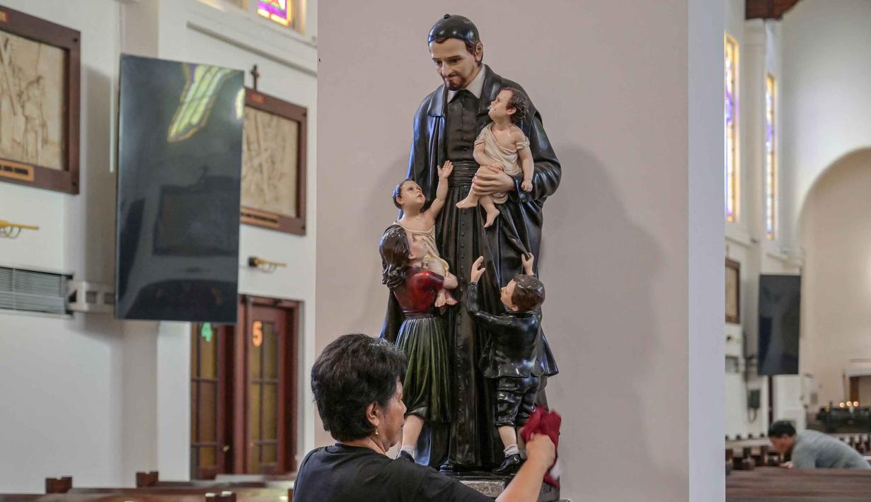 Tahun ini, Misa Natal mengangkat tema nasional, yakni "Allah Hadir Untuk Menyelamatkan Keluarga". Tampak dalam foto, seorang pekerja membersihkan patung Santo Vincent de Paul di Katedral Hati Kudus Yesus, yang dikenal secara lokal sebagai gereja "Hati Kudus Yesus", selama persiapan Misa Natal di Surabaya, Jawa Timur, pada Selasa 23 Desember 2025. (JUNI KRISWANTO/AFP)