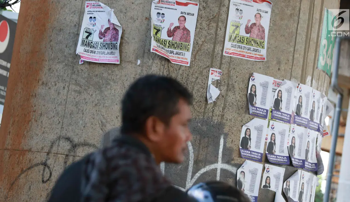 Warga berhenti dekat alat peraga kampanye calon legislatif yang menempel di sepanjang tiang penyangga Jalan Tol Desari, Jakarta, Kamis (25/4). Meskipun Pemilu serentak telah selesai, namun masih banyak APK di sejumlah sudut Ibu Kota dan menjadi sampah visual. (Liputan6.com/Immanuel Antonius)