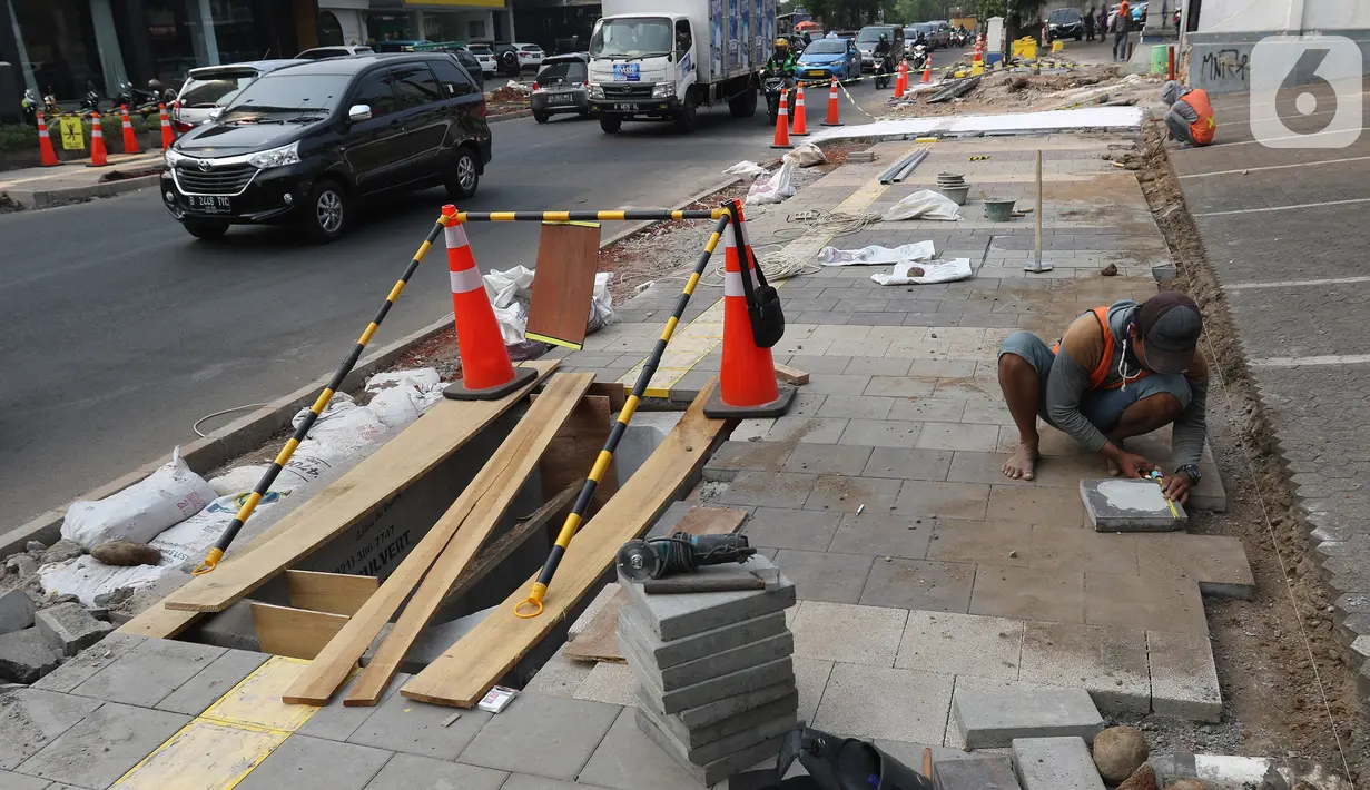 Pekerja mengerjakan proyek revitalisasi trotoar di kawasan Kemang, Jakarta Selatan, Selasa (15/10/2019). Pemerintah Provinsi DKI menargetkan pelebaran dan penataan trotoar ini akan rampung pada Desember 2019. (Liputan6.com/Herman Zakharia)