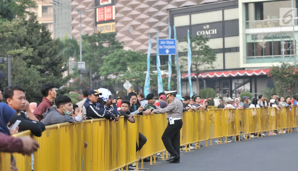 Warga berjejer dibalik pagar pembatas saat menunggu peserta lomba lari maraton Asian Games 2018 di kawasan MH Thamrin, Jakarta, Minggu (26/8). (Merdeka.com/Iqbal S. Nugroho)