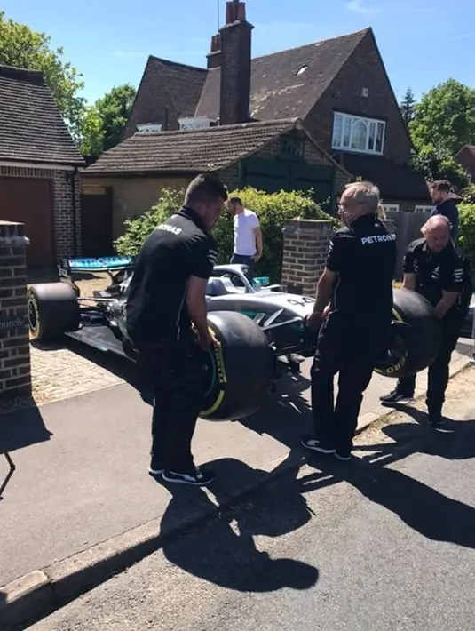 Sejumlah orang mengangkat mobil F1 dari Lewis Hamilton untuk bocah penderita kanker tulang langka Harry Shaw di Redhill, Surrey, Inggris, 13 Mei 2019. Setelah memenangi balapan F1 GP Spanyol, Lewis Hamilton mendedikasikan kemenangan yang diraihnya untuk Harry. (James Shaw/via REUTERS)