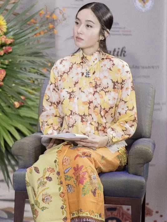Saat memandu acara, Nong Poy tampil mengenakan atasan warna kuning motif bunga yang serasi dengan kain lilit batiknya.Credit: @poydtreechada.
