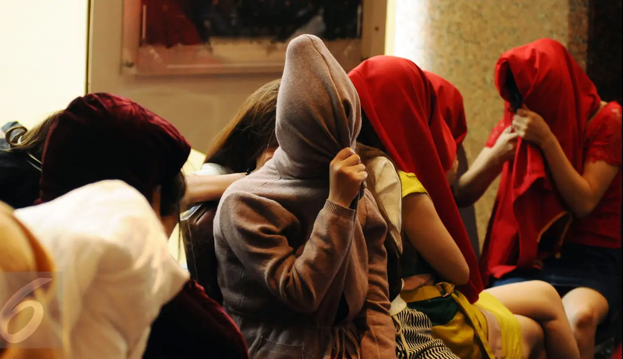 Puluhan perempuan warga negara asing illegal yang terjaring operasi pengawasan menutupi wajah saat rilis di Ditjen Imigrasi, Jakarta, Jumat (13/1). Diduga, para WNA tersebut bekerja sebagai pekerja seks komersial (PSK). (Liputan6.com/Helmi Fithriansyah)