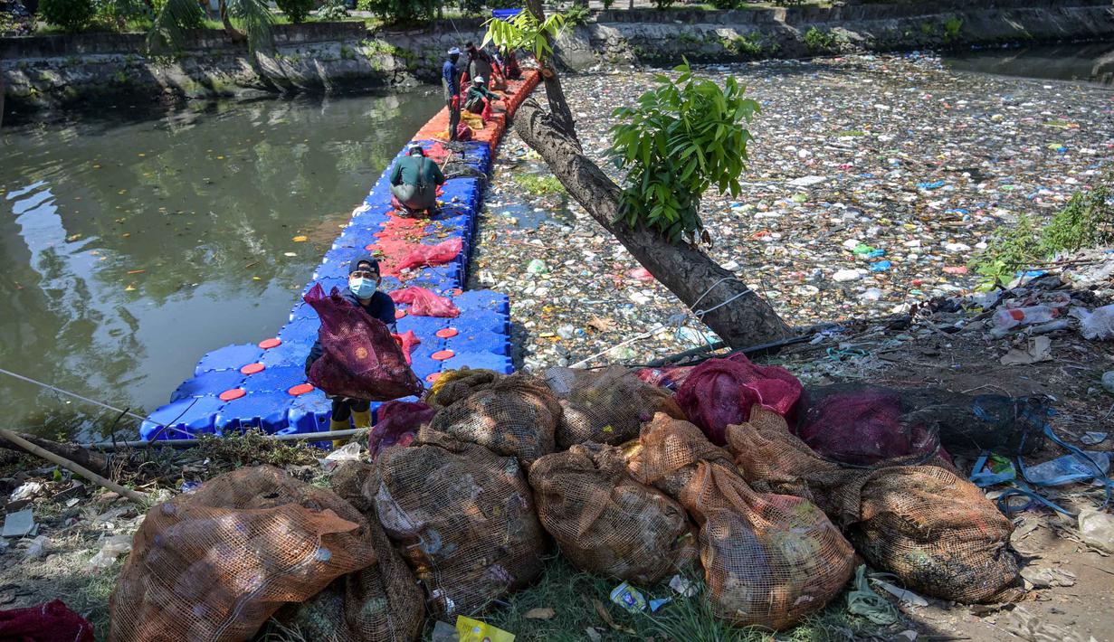 Upaya kolektif ini diharapkan dapat menghentikan kebiasaan membuang sampah ke sungai dan mengembalikan ekosistem sungai yang sehat bagi masyarakat. Tampak dalam foto, aktivis dari Ecoton (Ecological Observation and Wetlands Conservation) bersama pekerja dari Dinas Lingkungan Hidup Pemerintah Kota Surabaya, Jawa Timur, membersihkan sampah dari Sungai Kali Tebu, pada Senin 11 Mei 2026. (JUNI KRISWANTO/AFP)