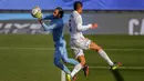 Bek Real Madrid, Raphael Varane, berebut bola dengan kiper Valencia, Jaume Domenech, pada laga Liga Spanyol di Stadion Alfredo Di Stefano, Minggu (14/2/2021). Real Madrid menang dengan skor 2-0. (AP/Manu Fernandez)