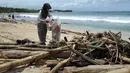 Seorang pengumpul sampah mengambil botol plastik dari puing-puing dan sampah di pesisir Pantai Kuta, Bali, Minggu (9/12). Kawasan pantai Kuta kembali dipenuhi oleh sampah hanyut terbawa oleh gelombang. (SONNY TUMBELAKA / AFP)